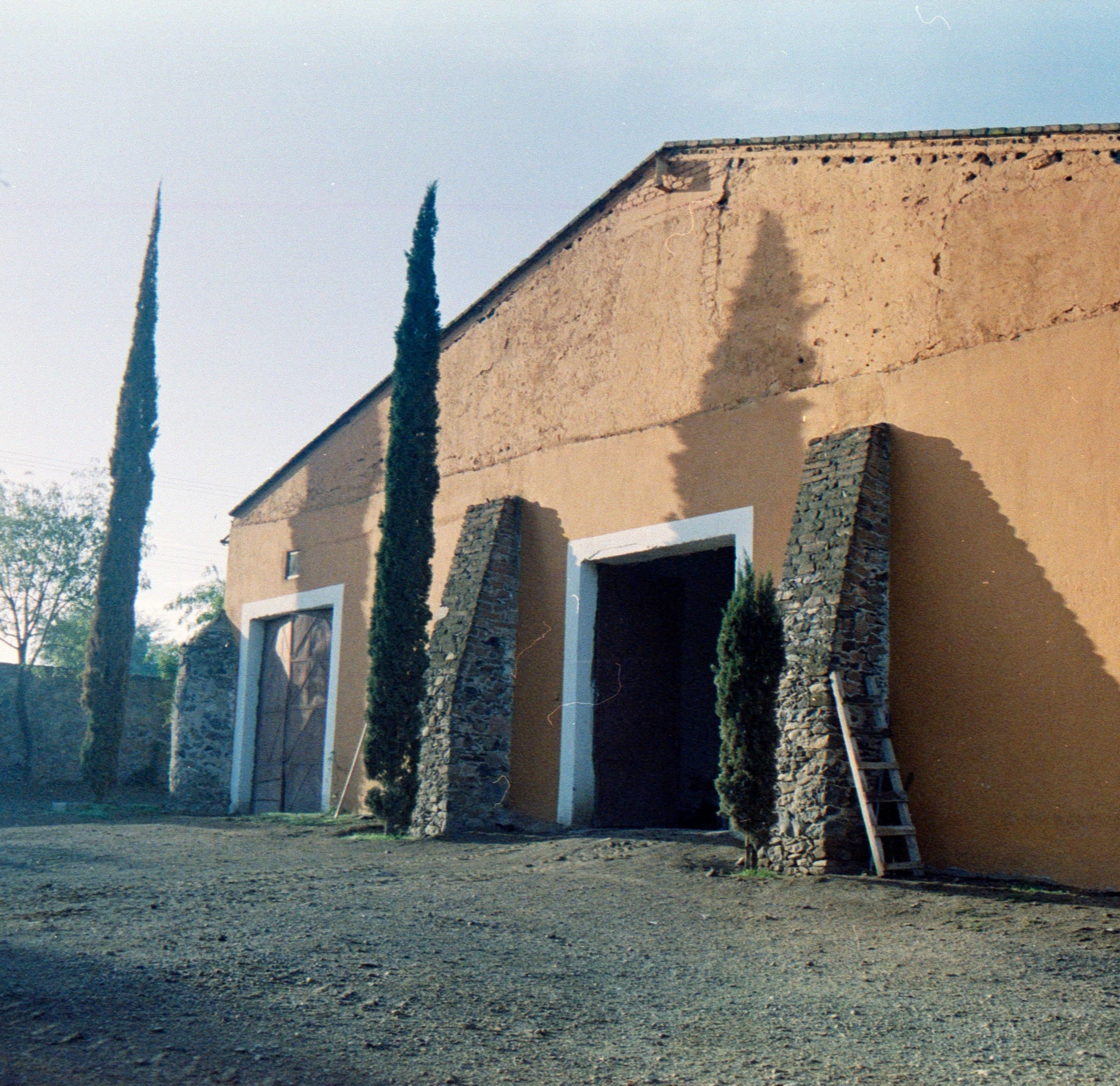 Destileria el Nacimiento Tequila El Ateo Large yellowish-brown building with stone columns and a clear sky.