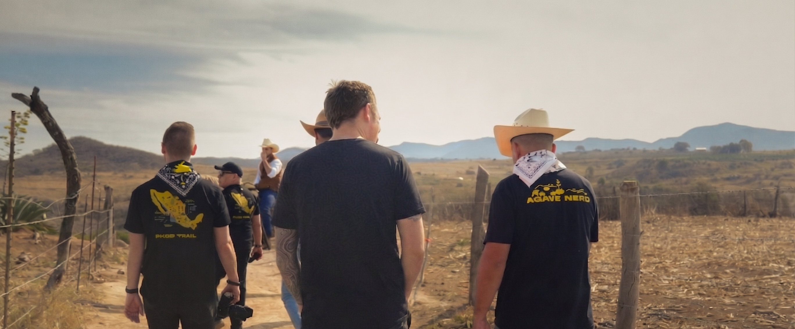 Group of people walking on a dirt path with mountains in the background