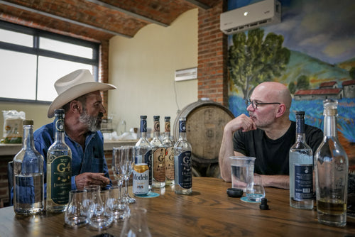 tequila exerience Two men sitting at a bar with liquor bottles and glasses.