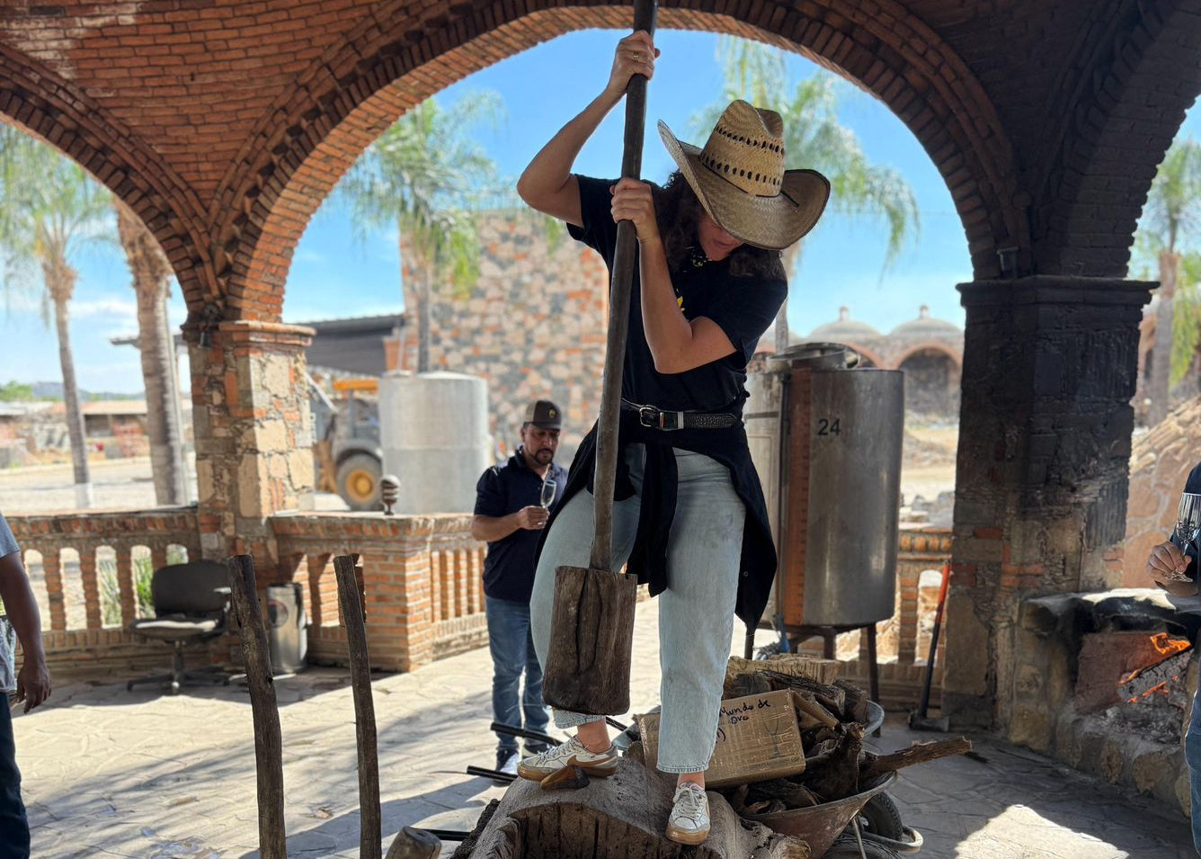 Person in cowboy hat using a long tool inside an archway with a rustic setting