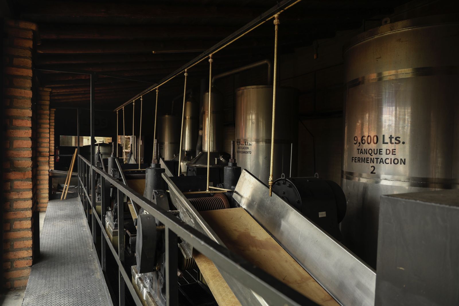 Alcohol fermentation tanks in a distillery with visible labels.