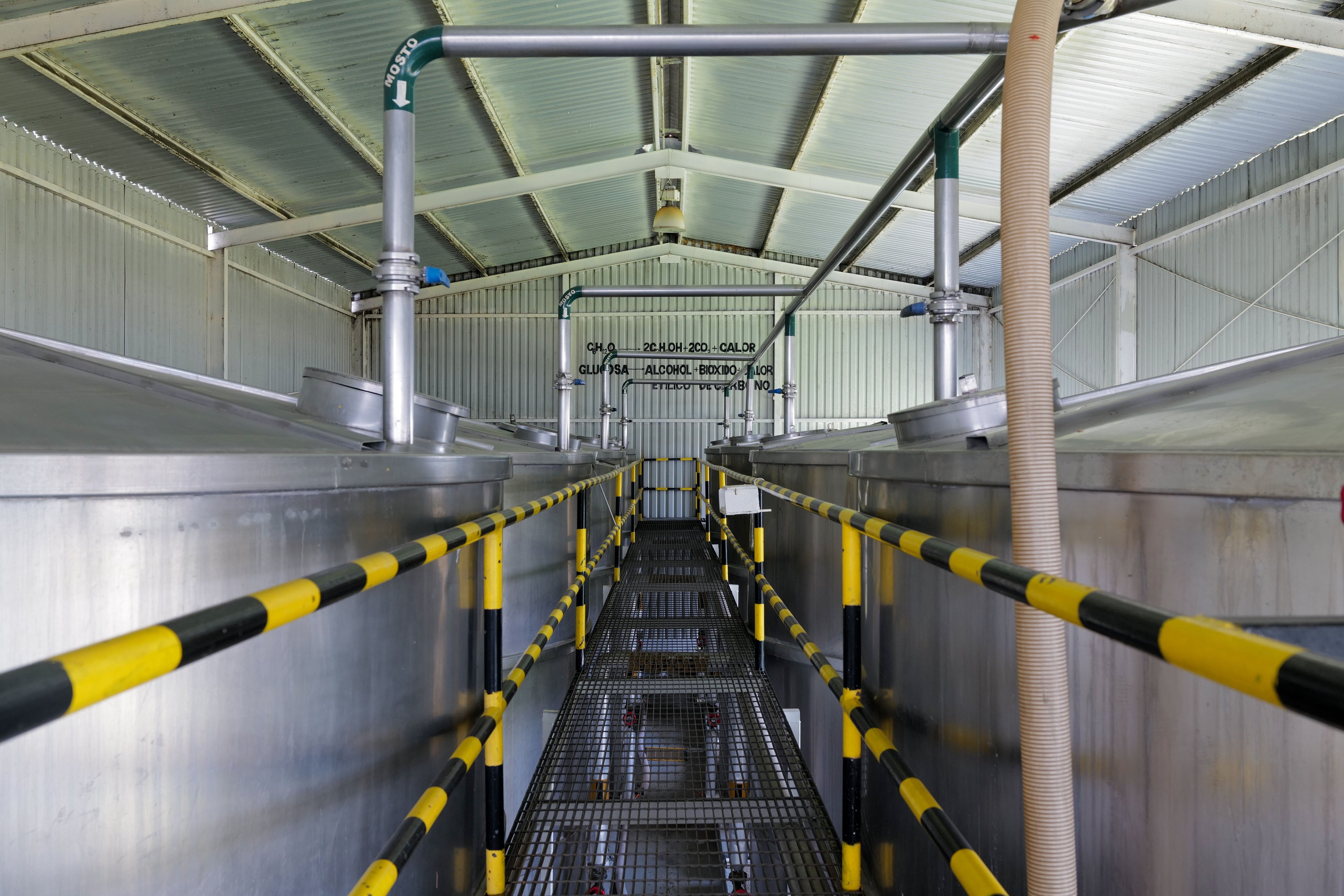 Industrial setting with large metal tanks and pipes inside a building