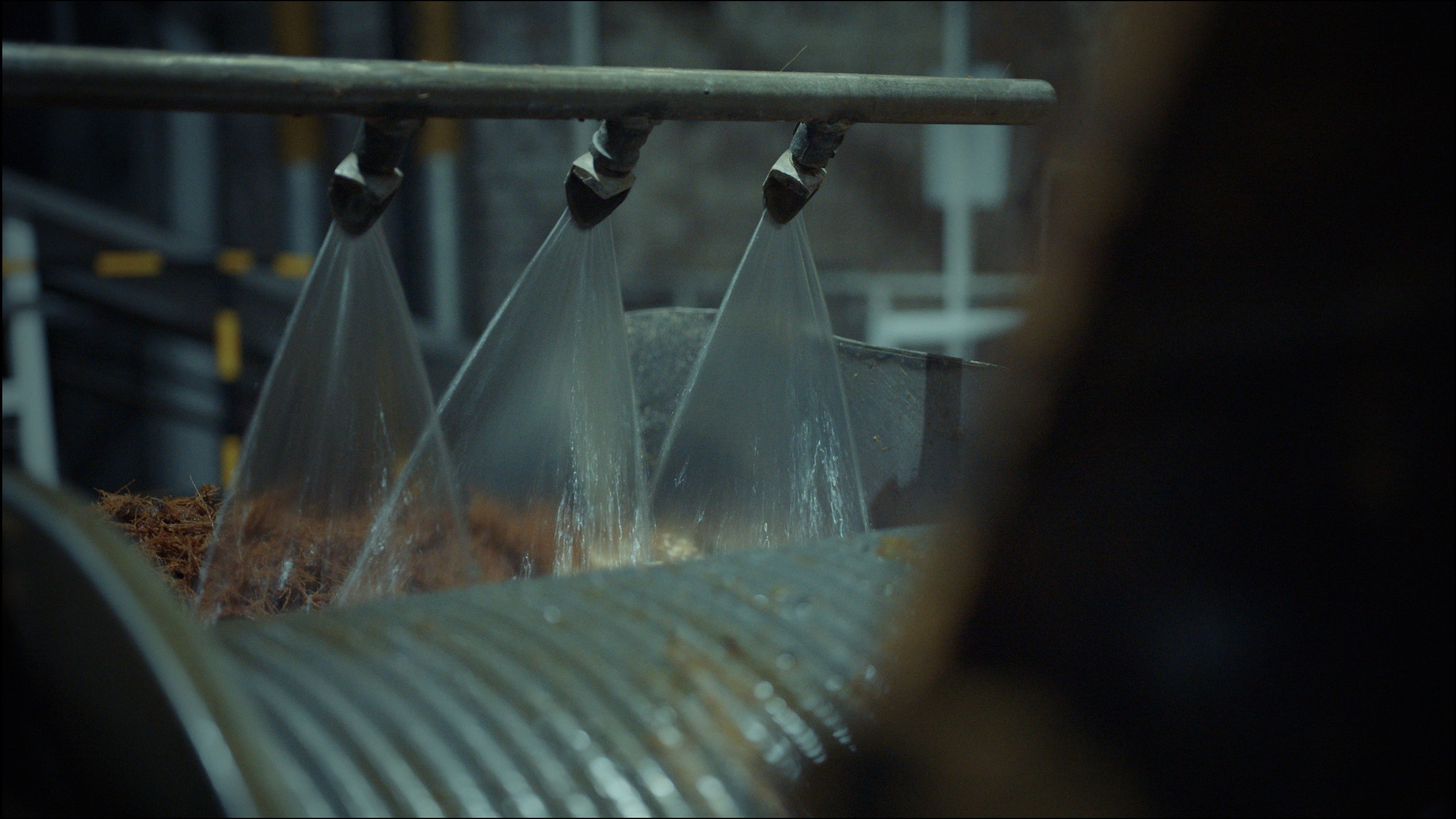 Close-up of a machine with a transparent hose dispensing liquid into a container.