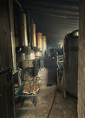Industrial interior with large metal tanks and pipes in a dimly lit room.